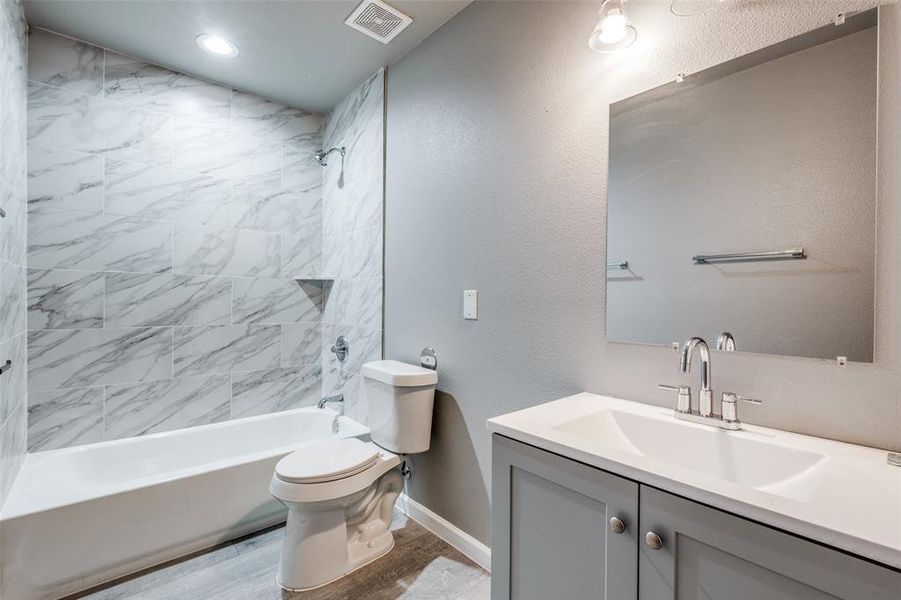 Full bathroom featuring toilet, vanity, and tiled shower / bath