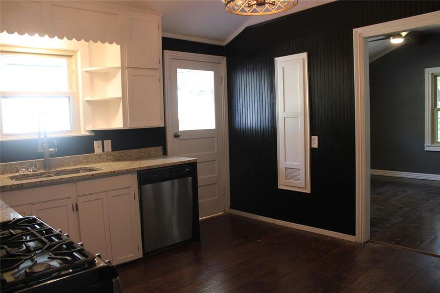 Kitchen featuring white cabinets, black gas range, stainless steel dishwasher, dark wood finished floors, and ornamental molding Kitchen featuring white cabinets, black gas range, stainless steel dishwasher, dark wood finished floors, and ornamental molding