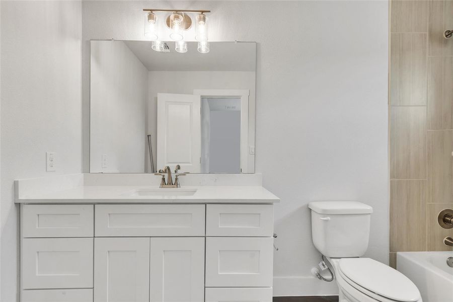 A spacious bathroom features a large vanity, mirror, and a sleek toilet.