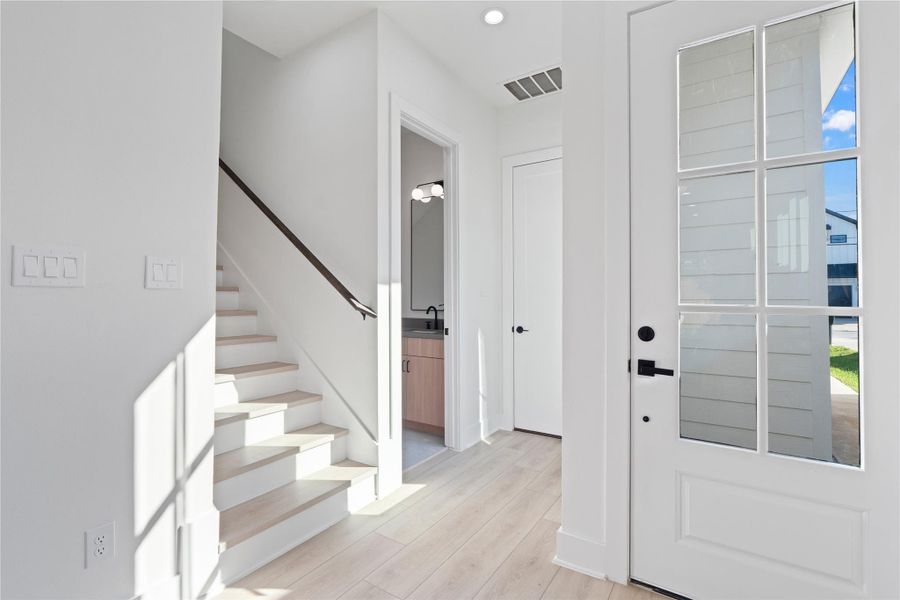 The welcoming entry foyer greets you with a clean, open feel, while the stairs are thoughtfully tucked away for a streamlined look. A conveniently located powder room, discreetly set apart from the living areas, adds both practicality and privacy. This functional yet inviting entry sets the tone for the modern farmhouse comfort found throughout the home.