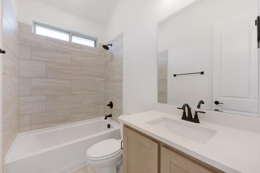 Bathroom with tiled tub-shower combo, white quartz vanity, and dark bronze fixtures
