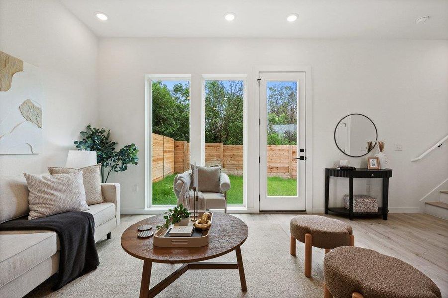 The living area features tall ceilings, recessed lighting, and large windows with a view of the private yard