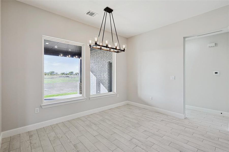 Empty room with a notable chandelier and light hardwood / wood-style flooring