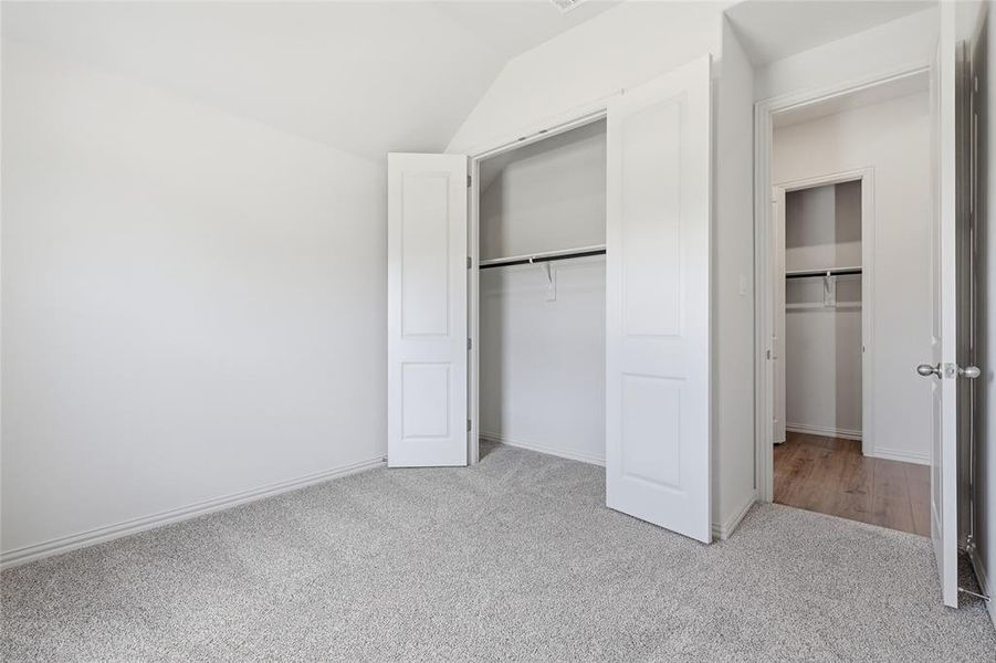 Unfurnished bedroom with light carpet, a closet, and vaulted ceiling