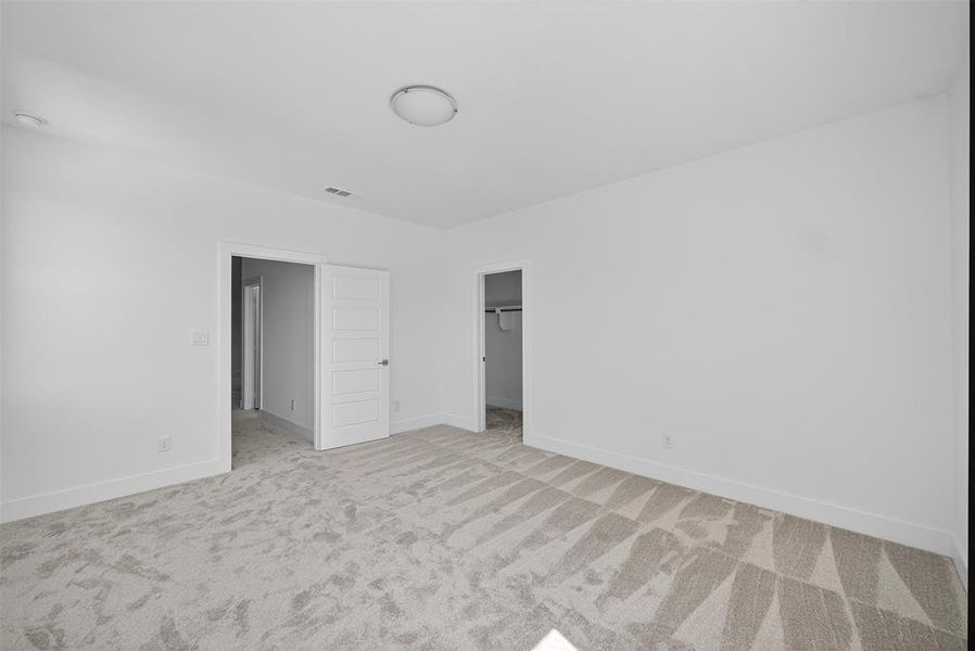Unfurnished bedroom featuring a walk in closet and light colored carpet
