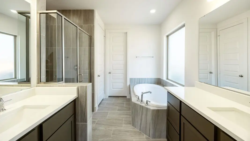 Full bath featuring a garden tub, a shower stall, two vanities, and recessed lighting