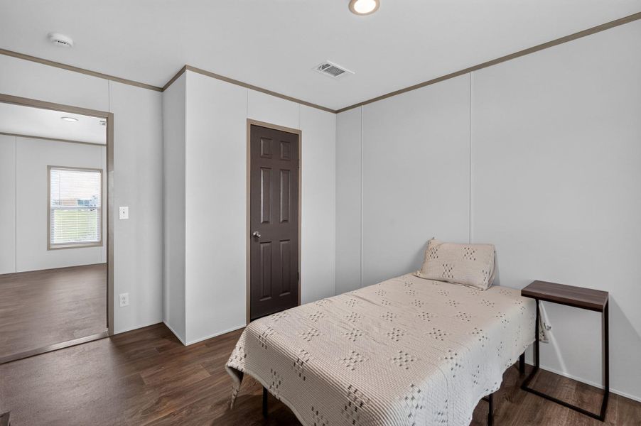 Hardwood-style flooring extends through this naturally lit bedroom, offering a warm and inviting atmosphere.
