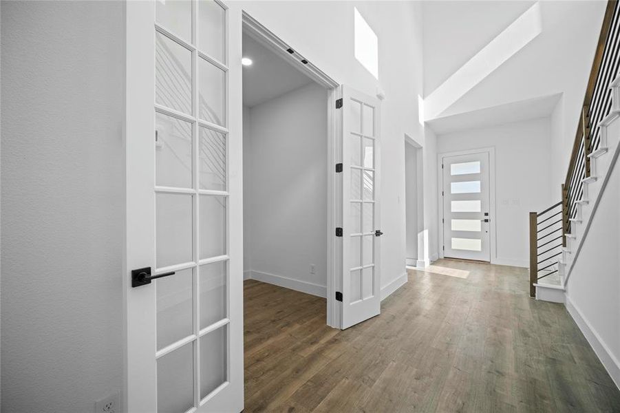 Hallway with wood finished floors, stairs, and french doors Hallway with wood finished floors, stairs, and french doors