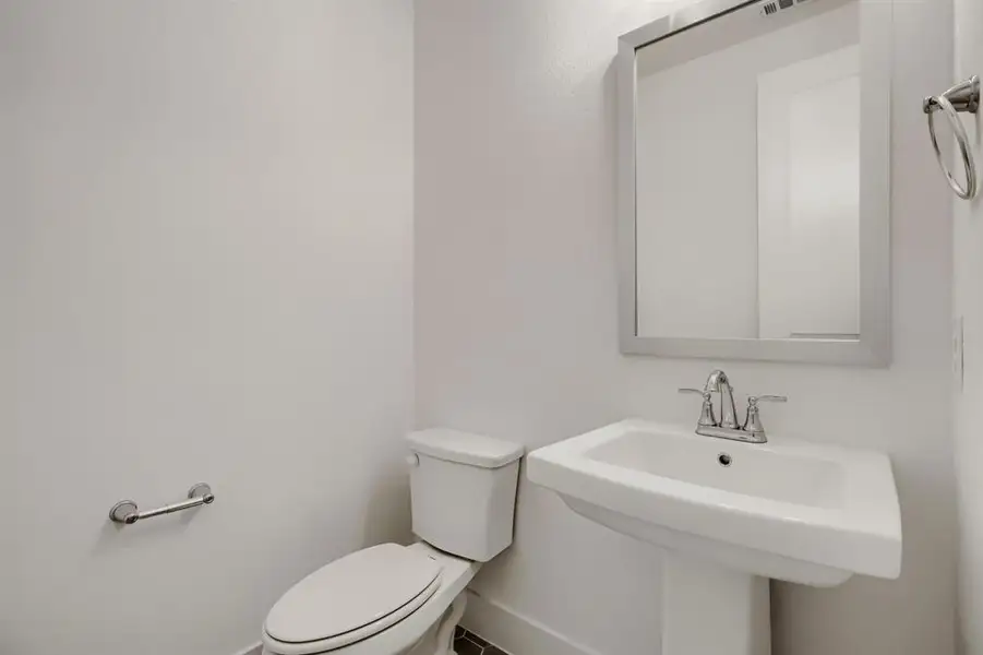 Pedestal sink with chrome faucet, framed mirror, and white toilet