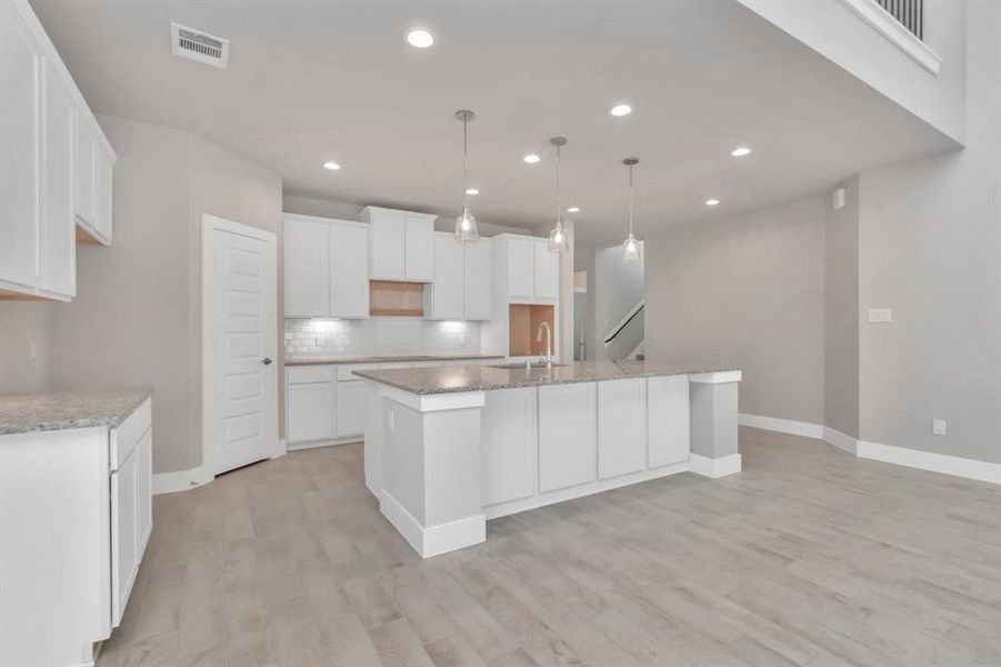 Take in another perspective of this impressive open and bright kitchen. Revel in the abundance of space designed to enhance functionality and elevate your culinary experience. Sample photo of completed home with similar floor plan. As-built interior colors and selections may vary.