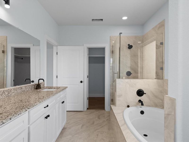 Bathroom featuring a walk in closet, a bath, and a stall shower
