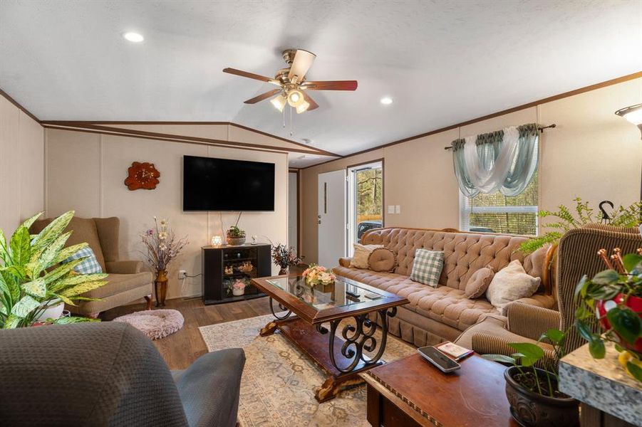 Living room with wood finished floors, recessed lighting, ceiling fan, vaulted ceiling, and crown molding Living room with wood finished floors, recessed lighting, ceiling fan, vaulted ceiling, and crown molding