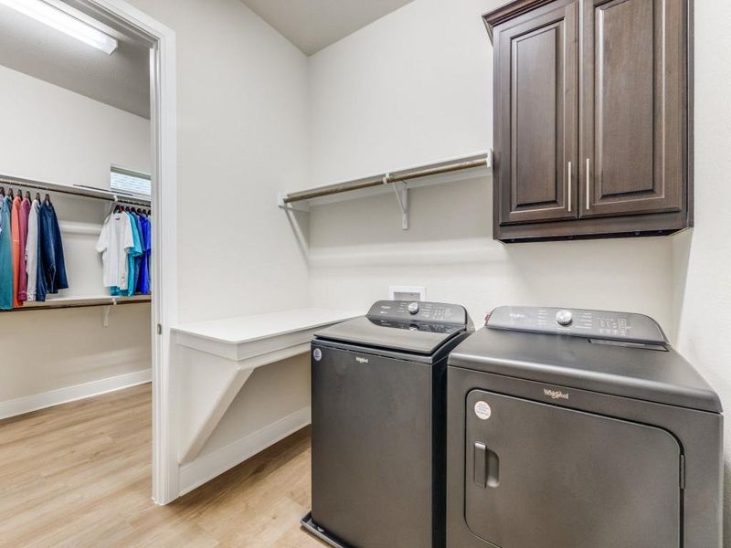 Utility room has cabinet, hanging rod and folding table.