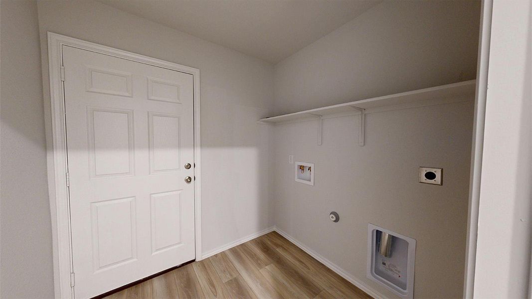 A dedicated laundry room with sturdy wood flooring and convenient upper shelving offers practicality.