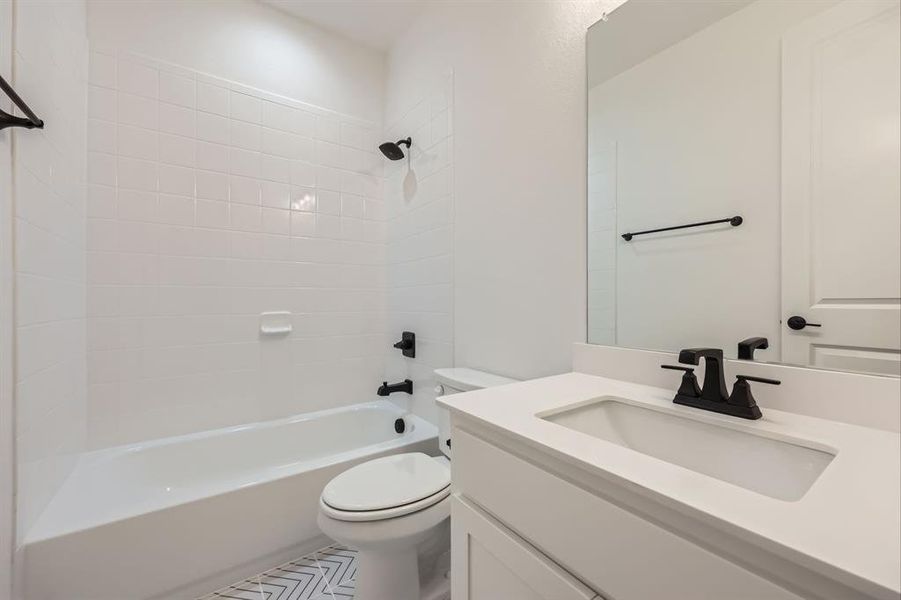 Full bathroom featuring tile patterned floors, vanity, toilet, and tiled shower / bath combo