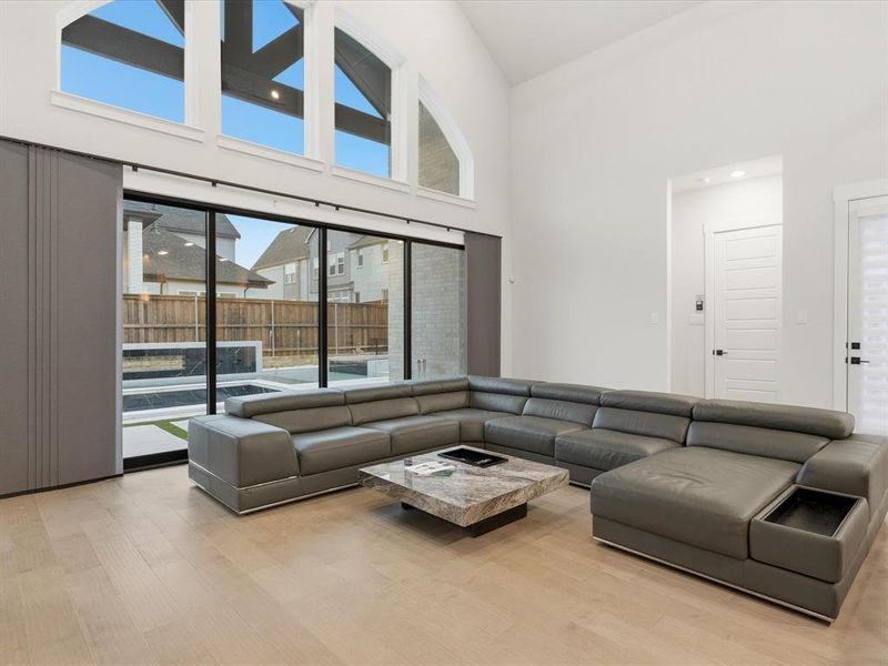 Vaulted ceilings in a living area featuring a wall of floor-to-ceiling windows, wood-finish flooring, and a modern sliding door system Vaulted ceilings in a living area featuring a wall of floor-to-ceiling windows, wood-finish flooring, and a modern sliding door system