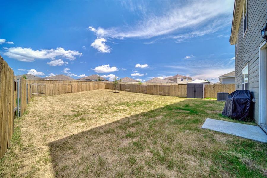 Fenced backyard featuring a shed