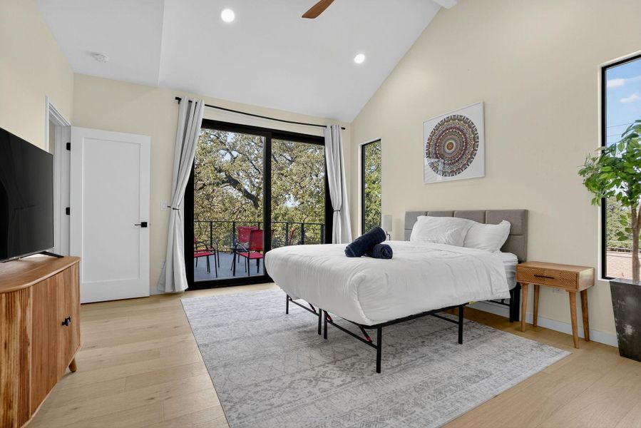 Bedroom featuring recessed lighting, high vaulted ceiling, access to exterior, light wood-style floors, and multiple windows