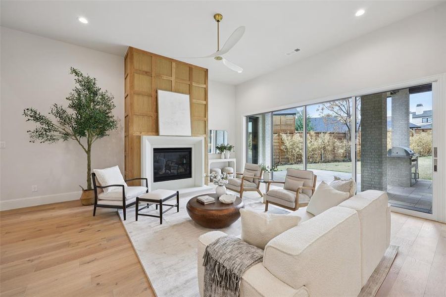 Living area featuring a ceiling fan, light wood-style flooring, a fireplace, and recessed lighting