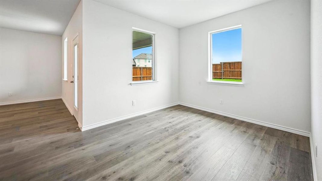 Spacious room featuring wood-finish flooring, white baseboards, and bright white walls
