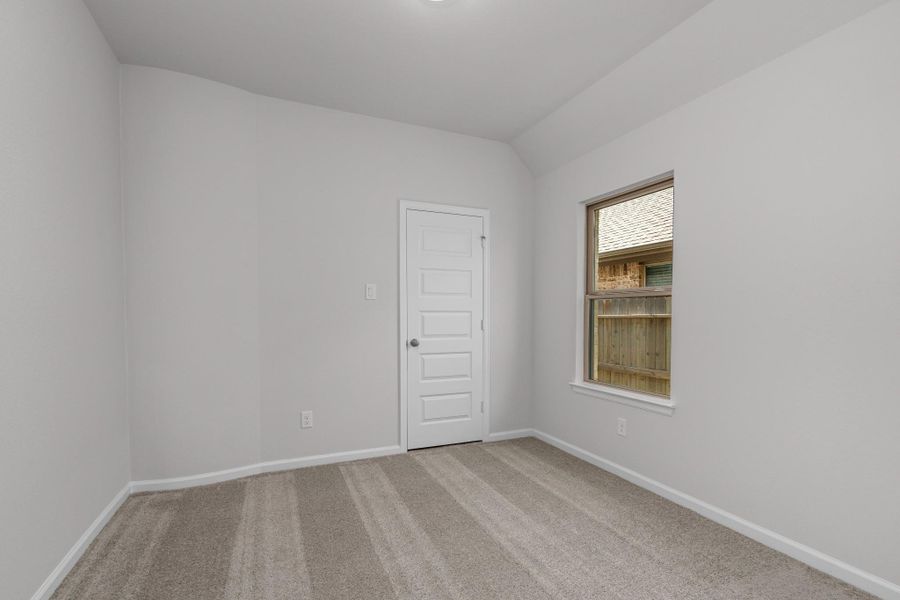 Secondary bedroom with neutral carpet, high ceiling and natural light.