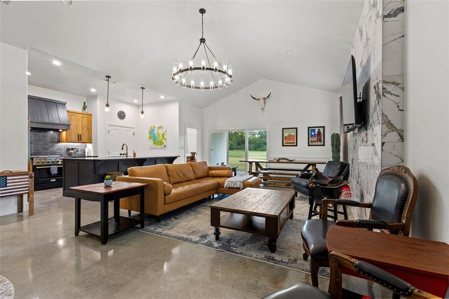 Living area with concrete floors, hanging lights, and vaulted ceiling
