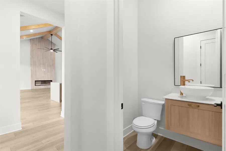 Half bathroom with vanity, light wood-style flooring, a fireplace, and ceiling fan