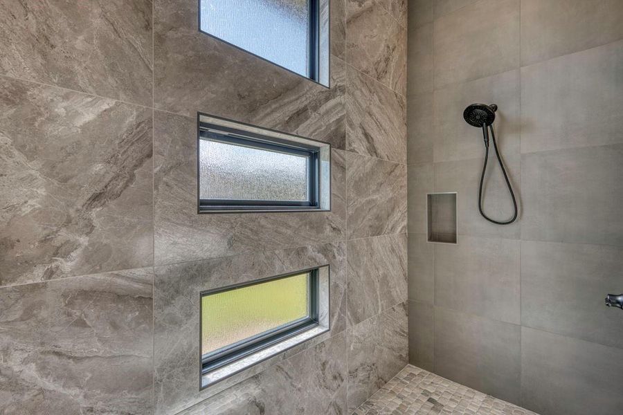Floor-to-ceiling stone tile and modern black fixtures elevate this walk-in shower design. Floor-to-ceiling stone tile and modern black fixtures elevate this walk-in shower design.