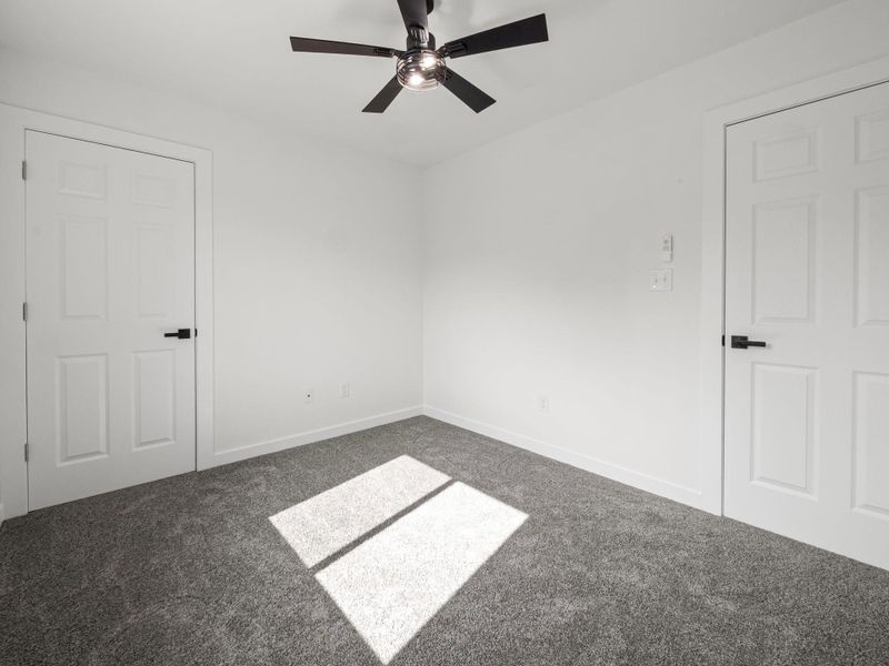 White-painted interior with gray carpeting and a black ceiling fan