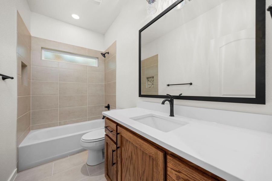A well-appointed bath features a sleek vanity, generous mirror, and a tiled tub with a privacy window. A well-appointed bath features a sleek vanity, generous mirror, and a tiled tub with a privacy window.
