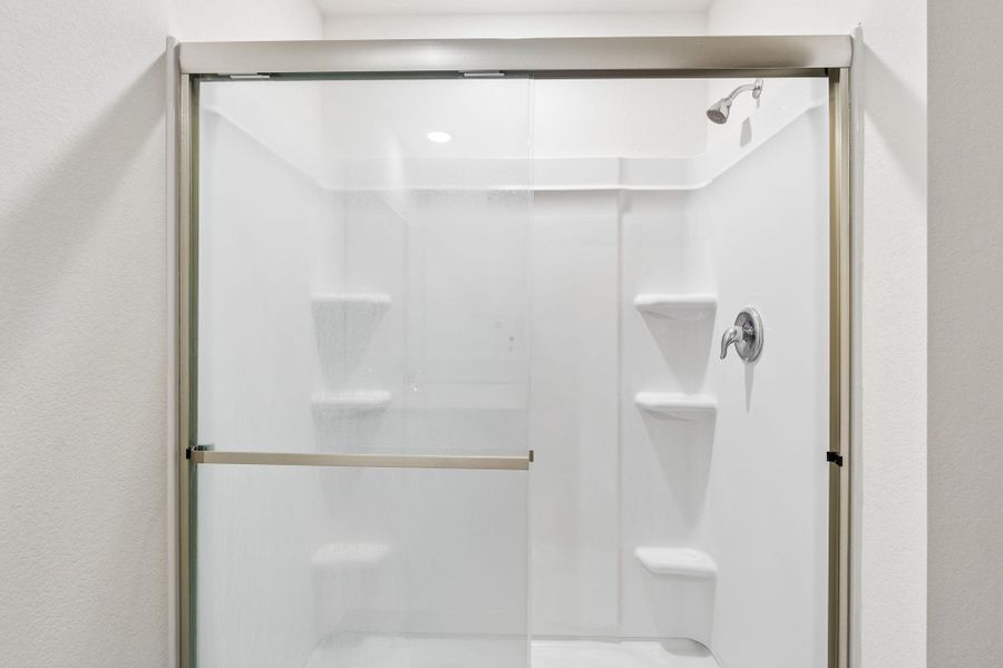Bathroom with a shower stall and a textured wall
