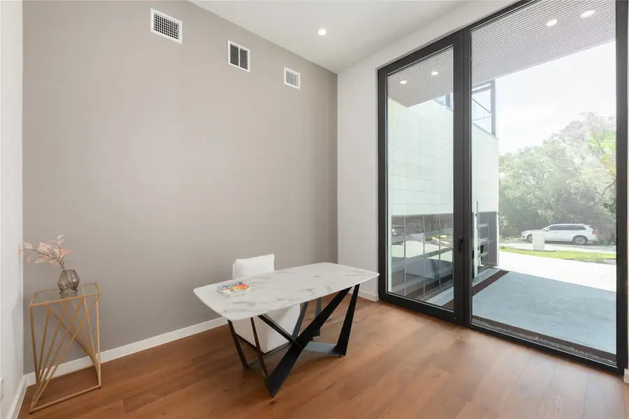 Floor-to-ceiling glass panels illuminate this dedicated work space with rich hardwood flooring.