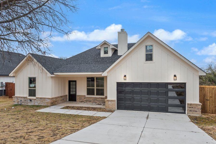 Modern farmhouse style home with board and batten siding, roof with shingles, a chimney, and covered porch