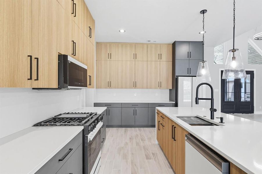 Kitchen with light brown cabinets, hanging light fixtures, appliances with stainless steel finishes, recessed lighting, and modern cabinets Kitchen with light brown cabinets, hanging light fixtures, appliances with stainless steel finishes, recessed lighting, and modern cabinets