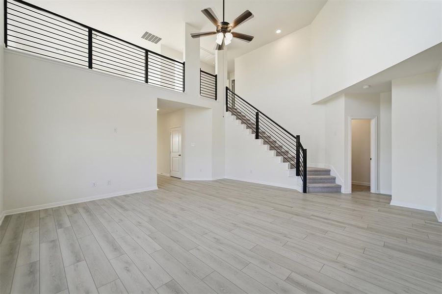 Two-story living area featuring wood-finish flooring and a contemporary black horizontal bar railing