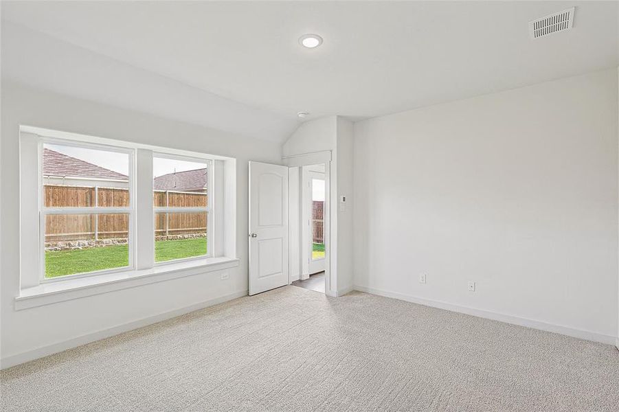 Empty room featuring light colored carpet and vaulted ceiling