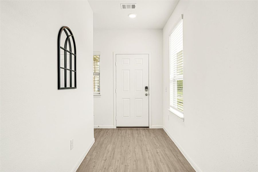 Crisp white hallway leading to a bedroom entrance, emphasizing a bright and airy layout.