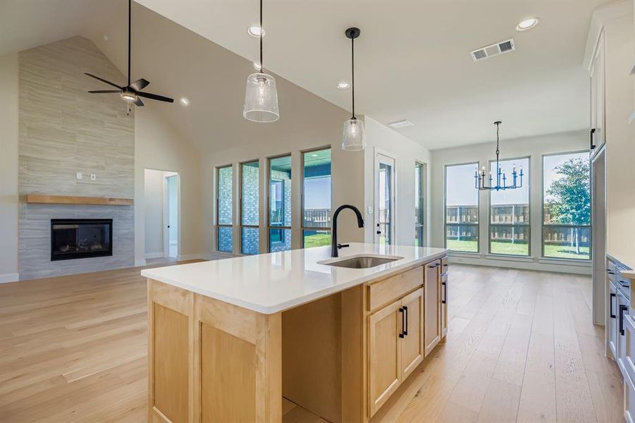 Kitchen featuring light brown cabinets, light wood-type flooring, hanging light fixtures, open floor plan, and plenty of natural light Kitchen featuring light brown cabinets, light wood-type flooring, hanging light fixtures, open floor plan, and plenty of natural light