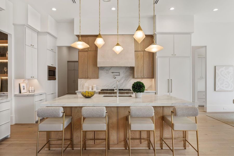 The kitchen is a true centerpiece, featuring a Thermador appliance package, panel-front cabinetry, and a large island with waterfall-edge quartzite countertops, all under designer lighting.