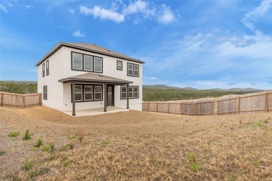 A private backyard featuring a new two-story residence, complete with a covered patio and sturdy wood fencing.