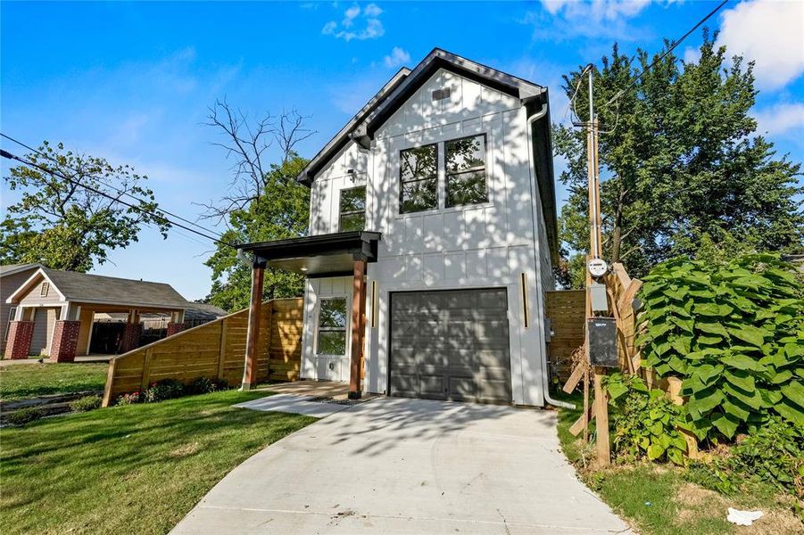 View of front facade featuring a front yard and a garage