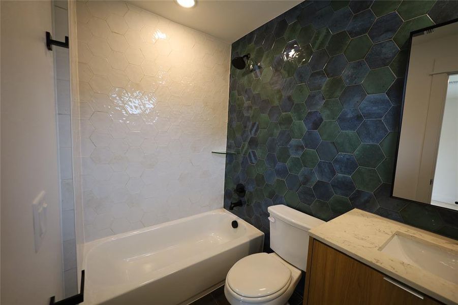 Bathroom featuring bathing tub / shower combination, tile walls, and vanity