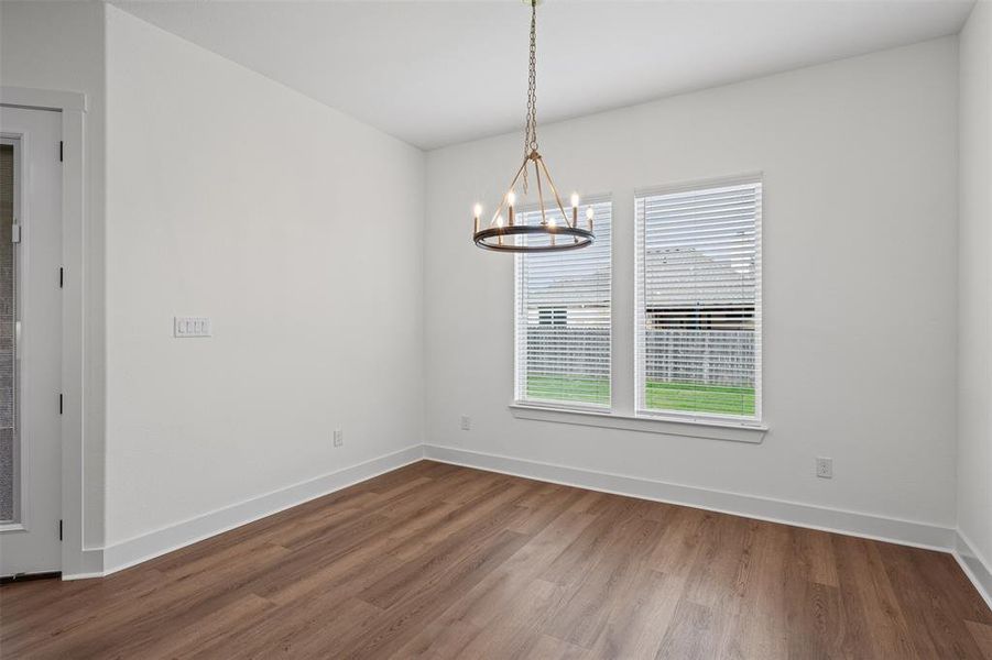 This room features hardwood flooring, white walls, and a contemporary chandelier