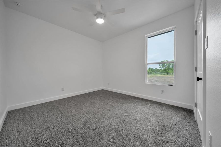 Carpeted empty room featuring ceiling fan