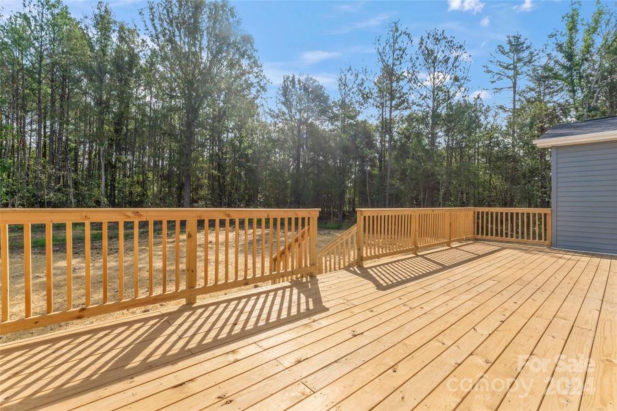 Large back deck overlooking wooden backyard