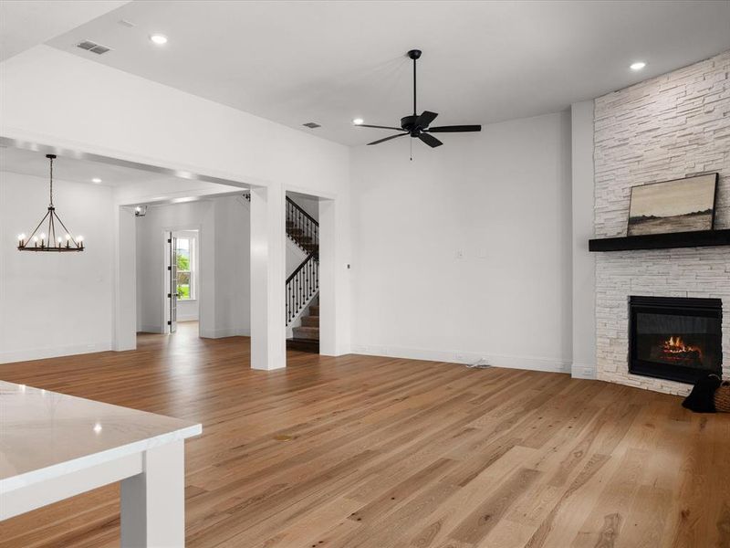 Unfurnished living room featuring light wood-style floors, recessed lighting, stairway, a stone fireplace, and ceiling fan