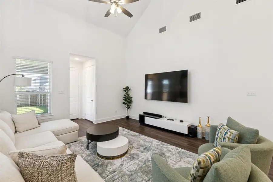 Living area featuring wood finished floors, high vaulted ceiling, and a ceiling fan Living area featuring wood finished floors, high vaulted ceiling, and a ceiling fan
