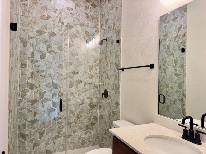 Bathroom with a textured wall, vanity, and a shower stall