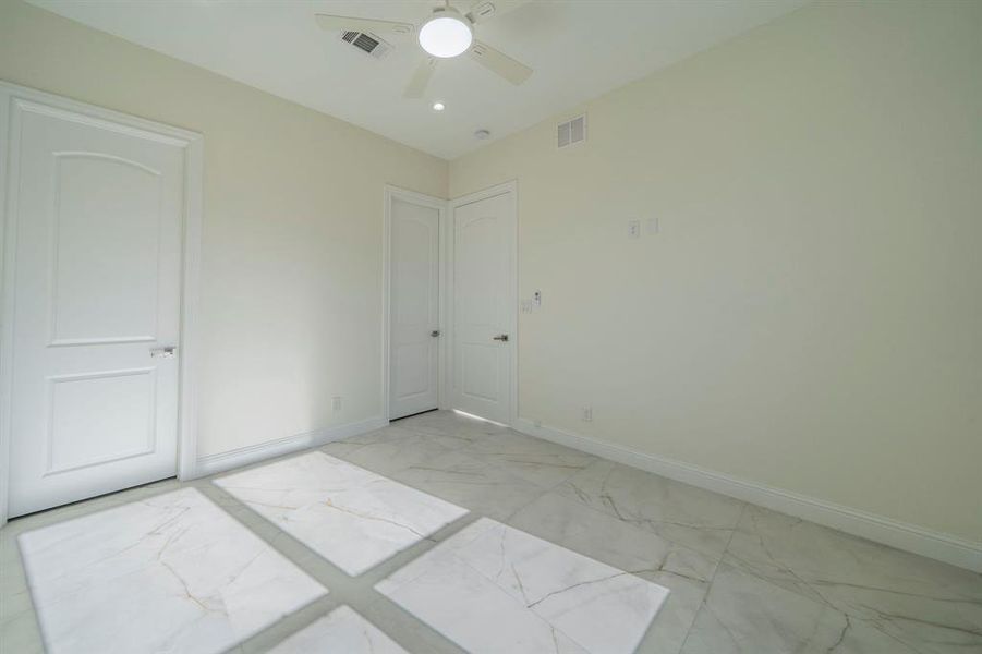 Unfurnished bedroom with light marble finish flooring and ceiling fan Unfurnished bedroom with light marble finish flooring and ceiling fan