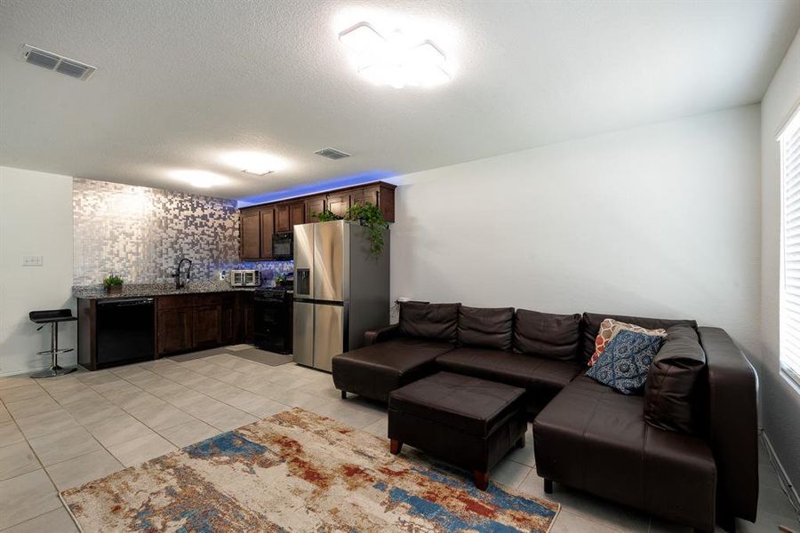 Living room with a textured ceiling, light tile patterned floors, a wealth of natural light, and sink